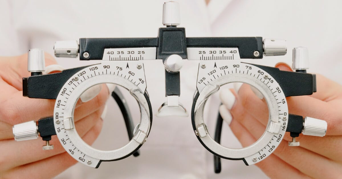 Crop unrecognizable female optometrist with trial frame in hands