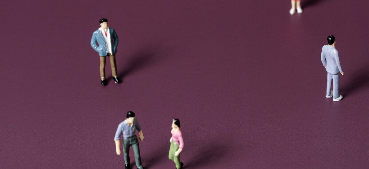 Five miniature figurines of people against a dark purple background. Two figurines look to be having a conflict and the other three are standing separate from each other.