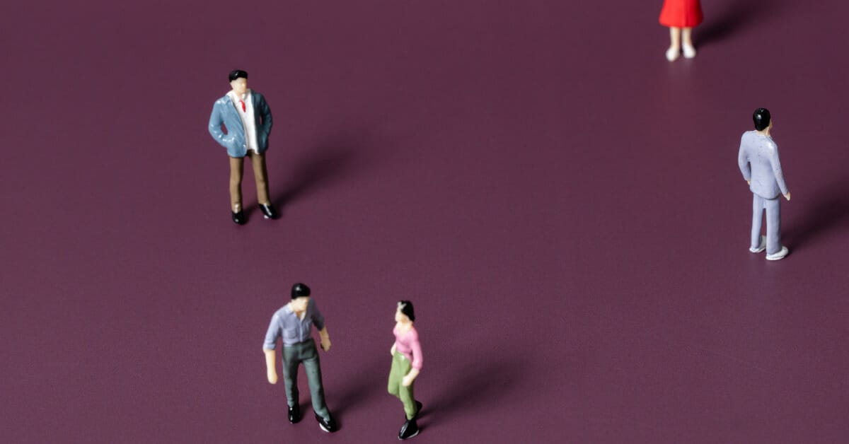 Five miniature figurines of people against a dark purple background. Two figurines look to be having a conflict and the other three are standing separate from each other.