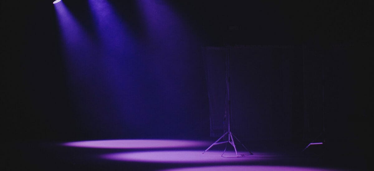 purple lights shine down on a dark stage