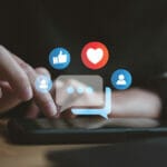 a smartphone with icons and graphics displaying above it to signify social media strategy