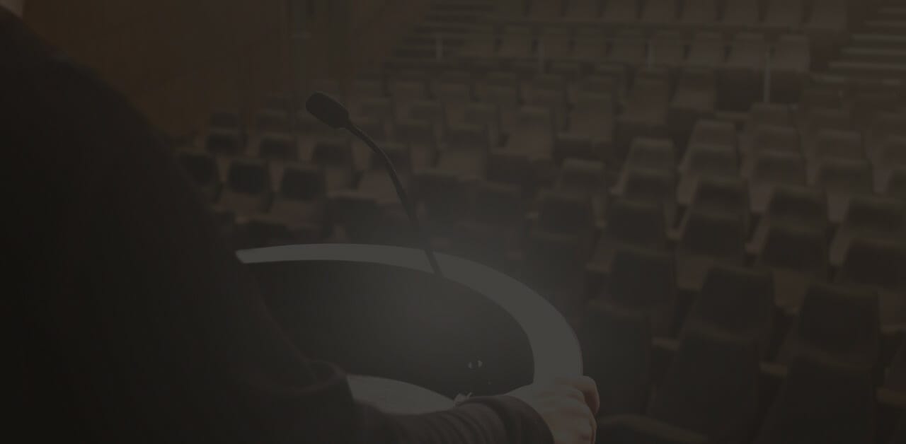 A podium with microphone on a stage with an empty audience; signaling leadership & how to communicate effectively.