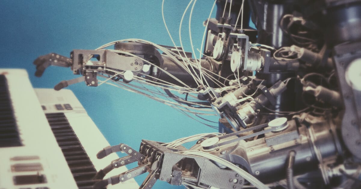 A robot made of silver metal playing a piano keyboard in front of a blue background