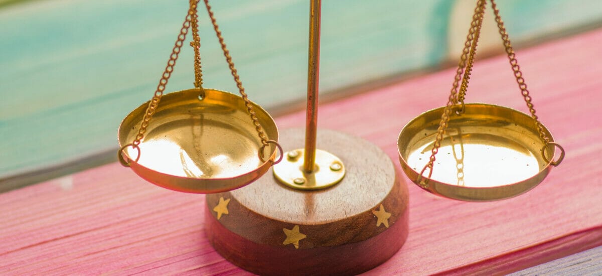 An empty brass scale on a wooden rainbow striped table