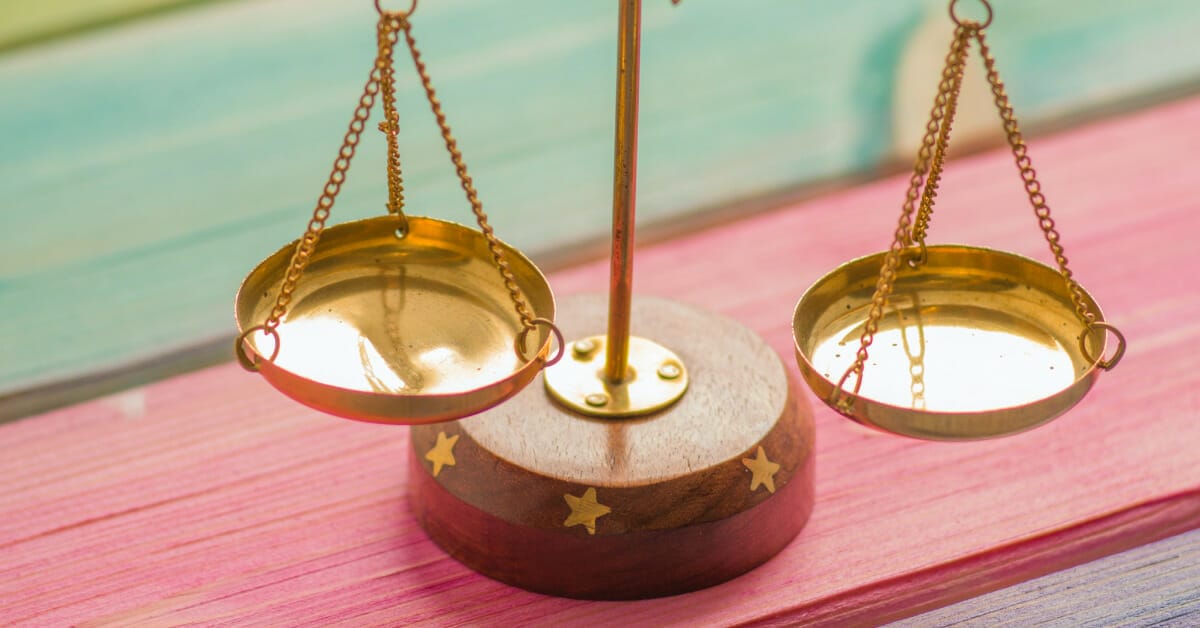An empty brass scale on a wooden rainbow striped table