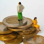 Man and woman sitting on unequal levels of coins