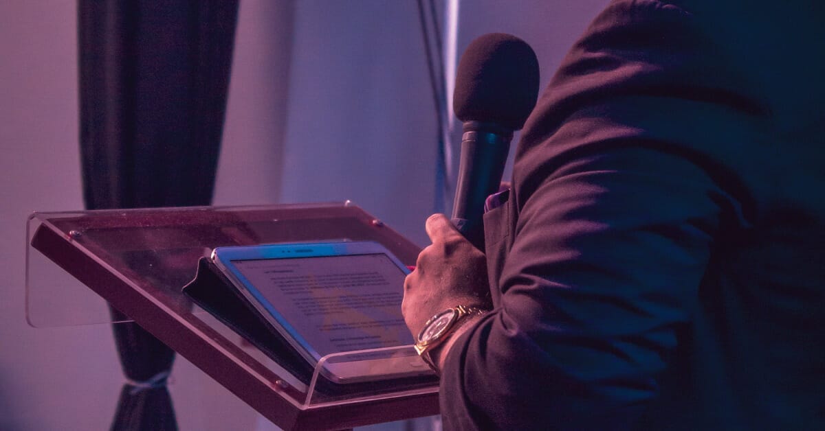 man speaking at a lecturn with microphone