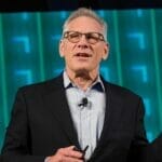 Image of Stew Friedman wearing a black suit jacket and light blue shirt in front of a teal blue background