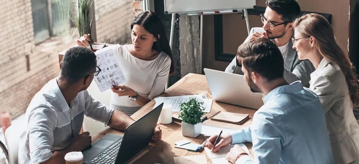 people meeting around a table and working - How to Craft a Thought Leadership Strategy - Thought Leadership Strategy