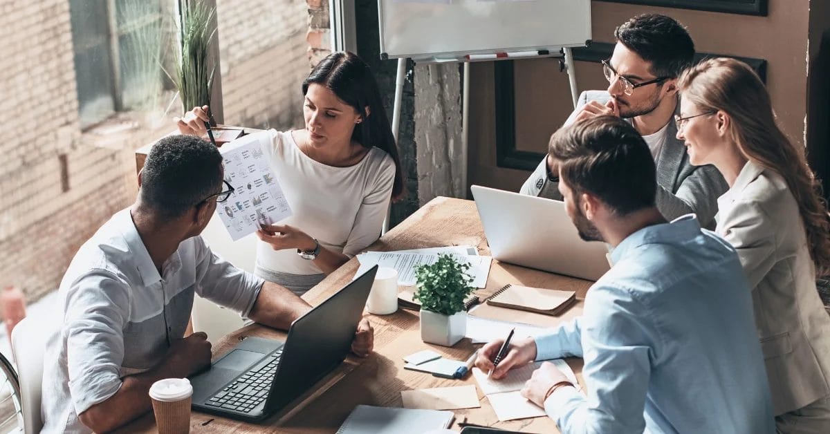 people meeting around a table and working - How to Craft a Thought Leadership Strategy - Thought Leadership Strategy