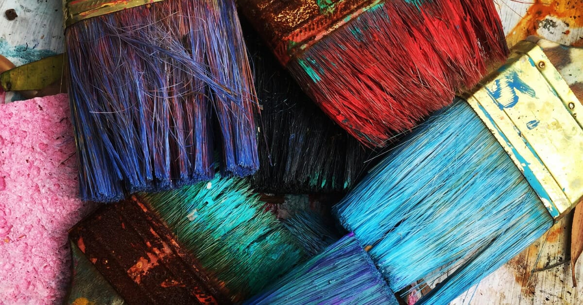 Several rainbow paintbrushes on a rainbow background showing diversity