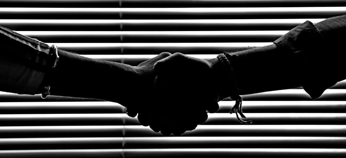 handshake in front of window blinds in black and white
