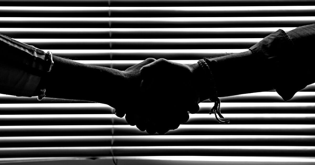 handshake in front of window blinds in black and white